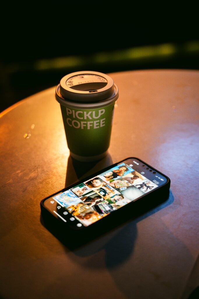 A stylish coffee cup beside a smartphone on a table, evoking a cozy indoor ambiance.